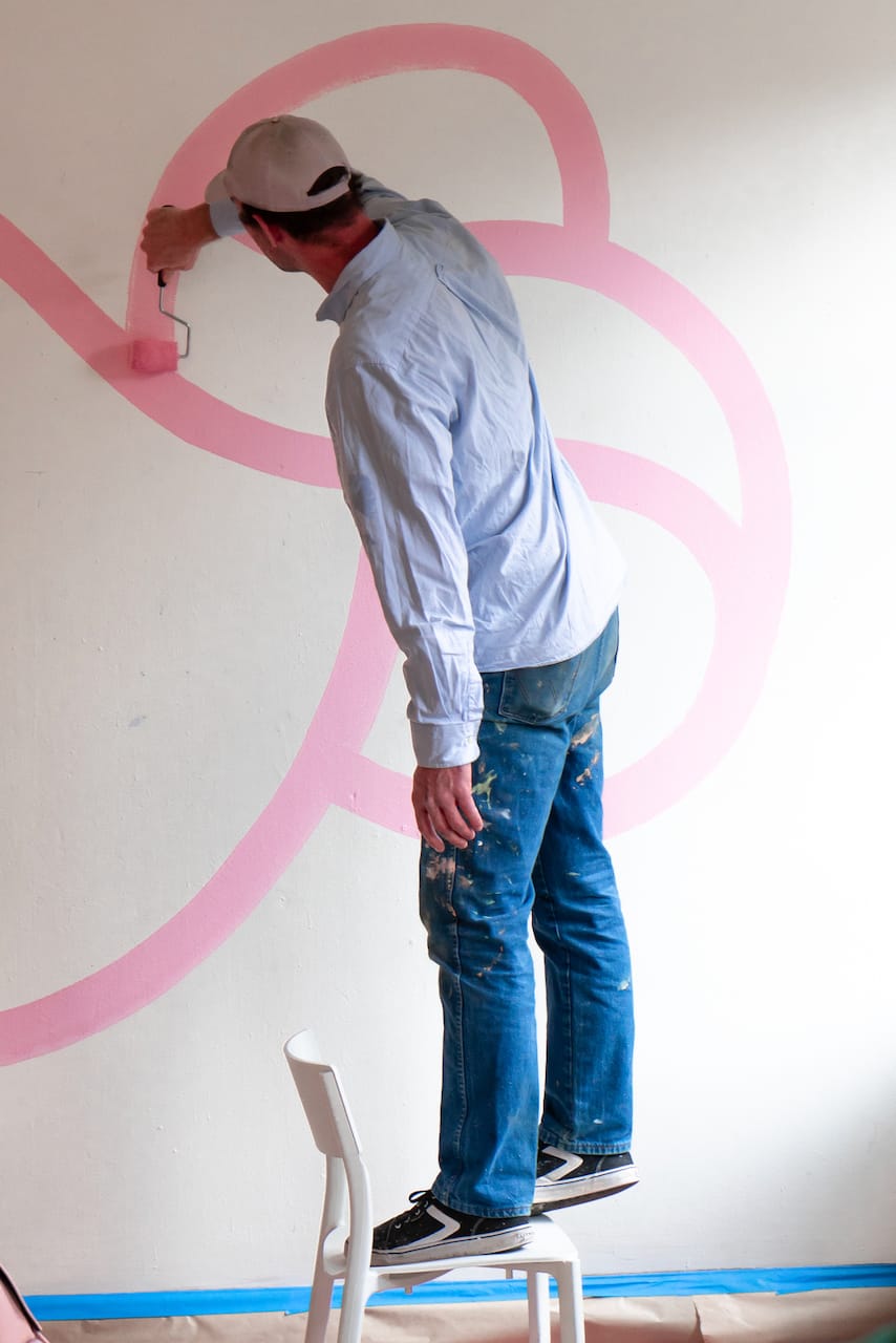 The muralist at work on a stool.