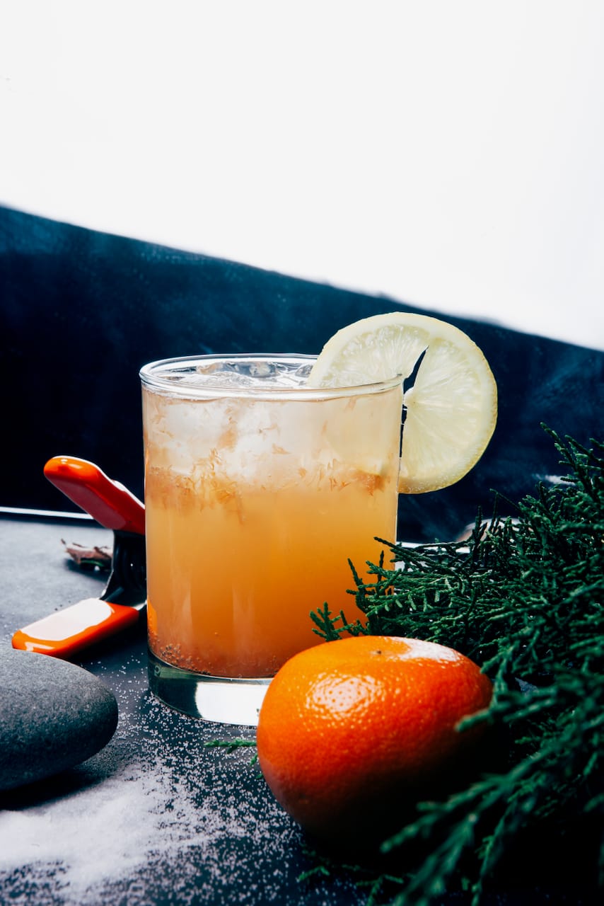 A tonic with a lemon wheel, an orange, and cedar.